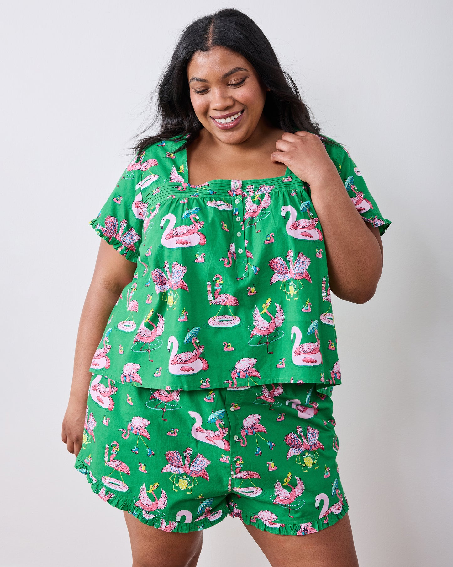 Front view of the green flamingo-print pintuck top and matching ruffled shorts