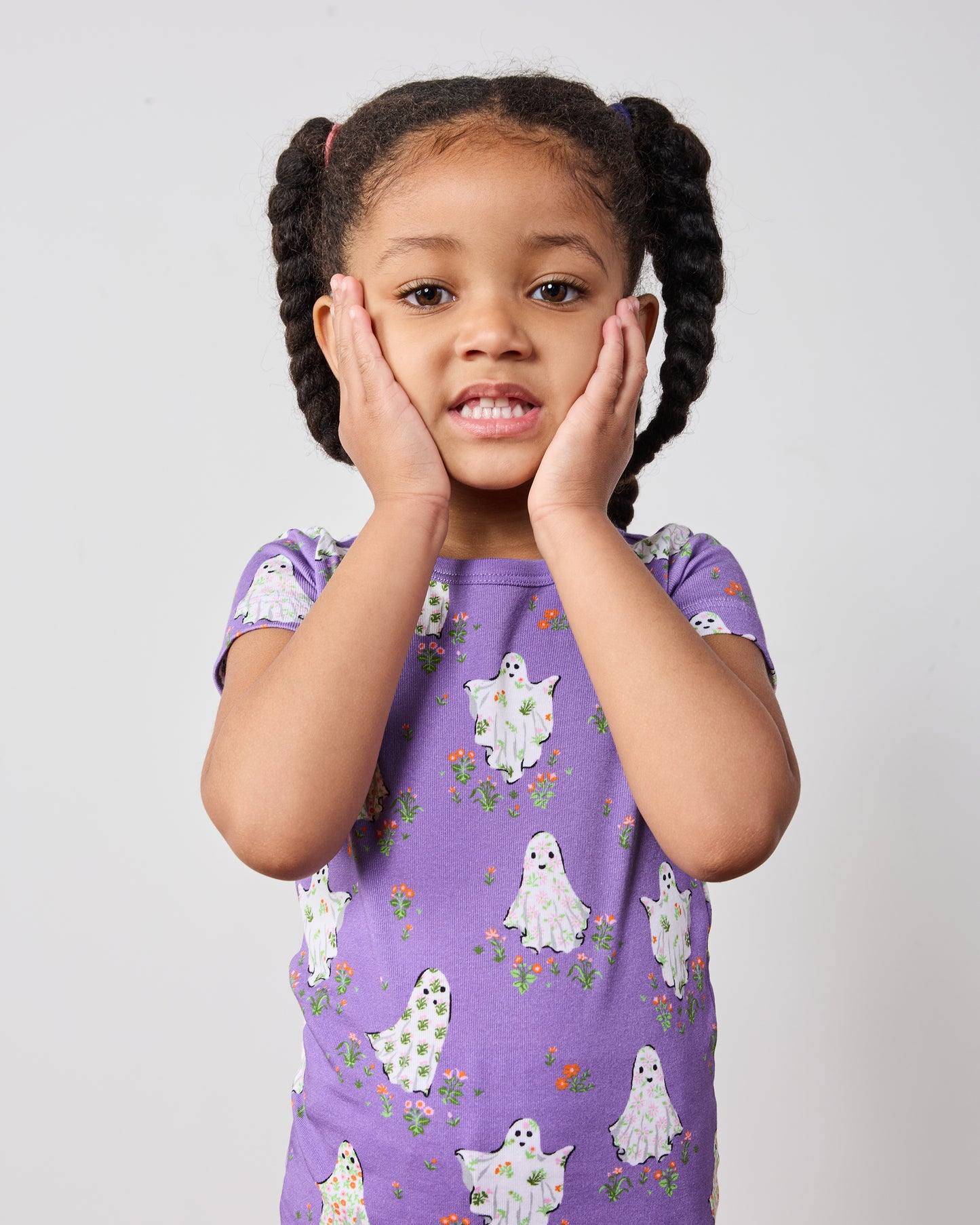 Close front view of a child wearing a purple short-sleeve ghost-print pajama top