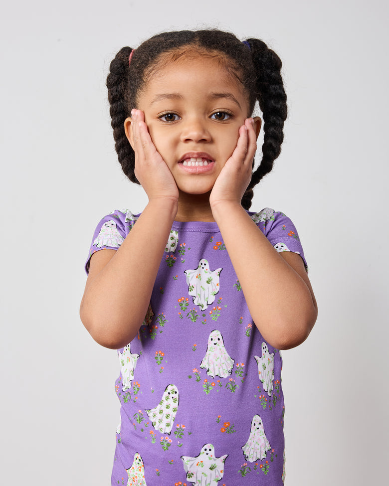 Close front view of a child wearing a purple short-sleeve ghost-print pajama top