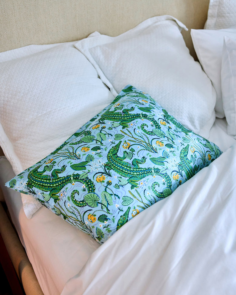 Alligator and foliage print pillowcase arranged on a bed with white bedding