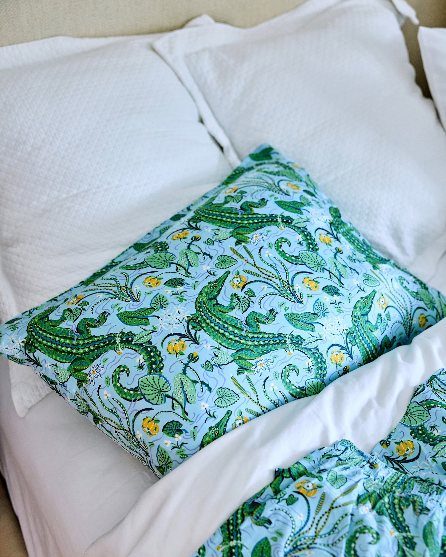 Alligator and foliage print pillowcase on a bed, with matching shorts in the foreground