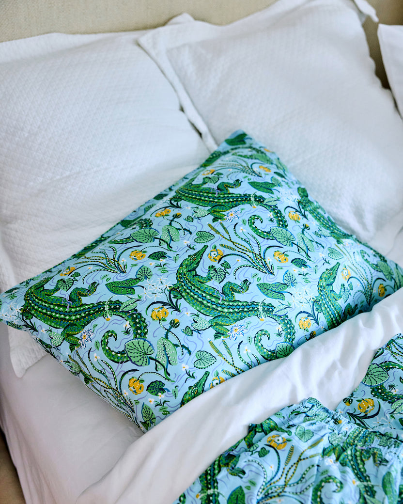 Alligator and foliage print pillowcase on a bed, with matching shorts in the foreground