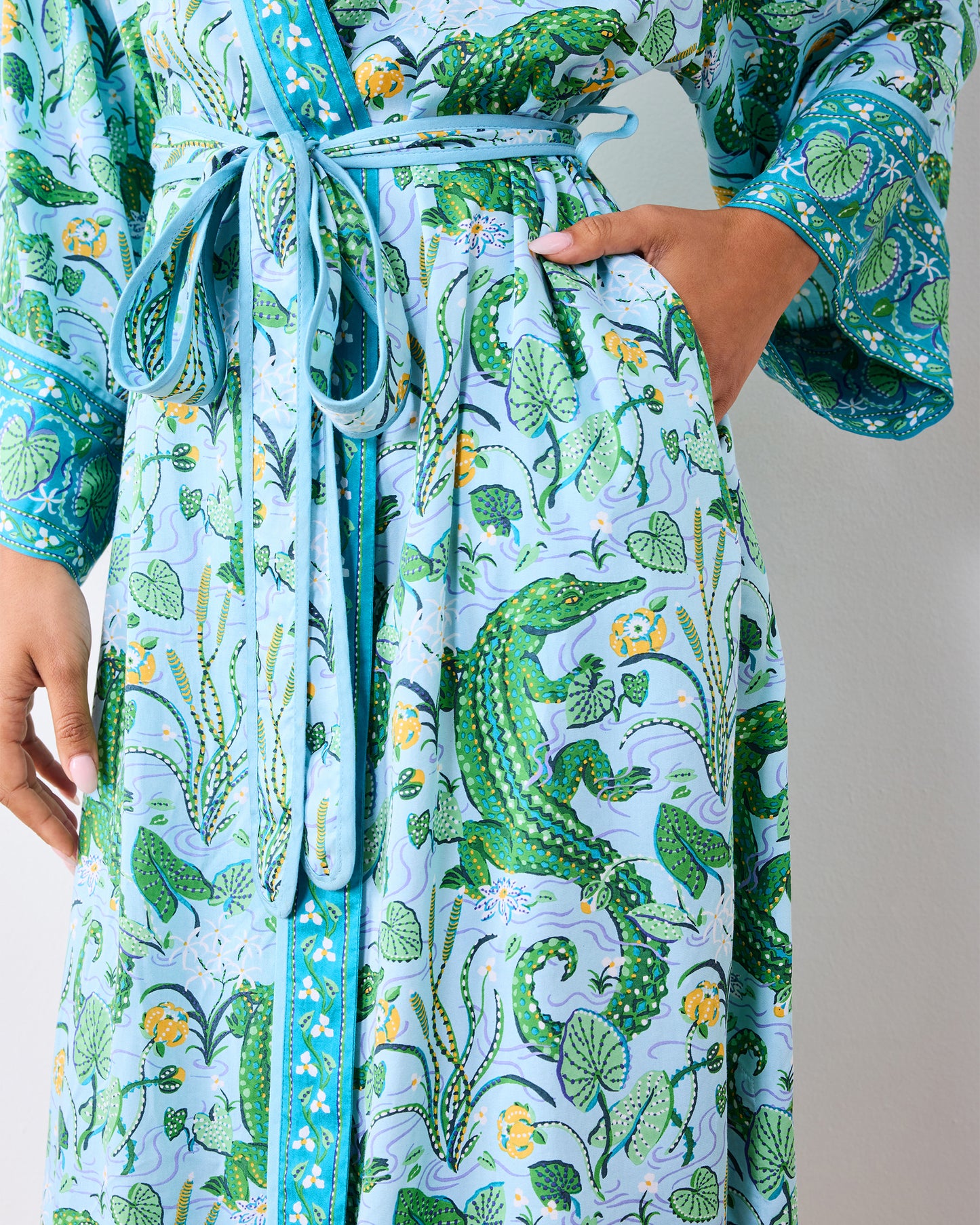 Close-up of the alligator-print robe's tied belt, front trim, cuff, and pocket