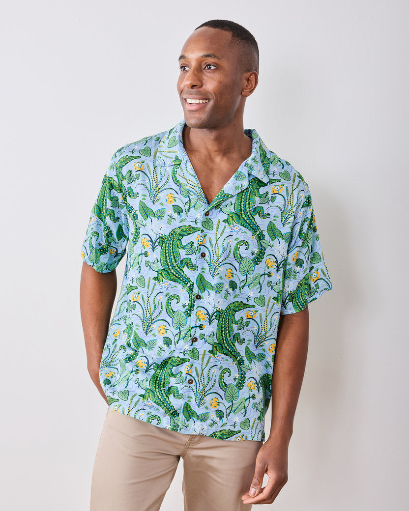 Front view of a model wearing the Blue Lagoon camp shirt with an alligator and foliage print