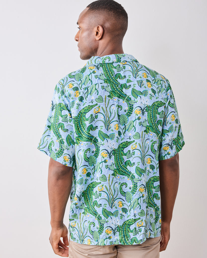 Back view of a model wearing the Blue Lagoon camp shirt with an alligator and foliage print