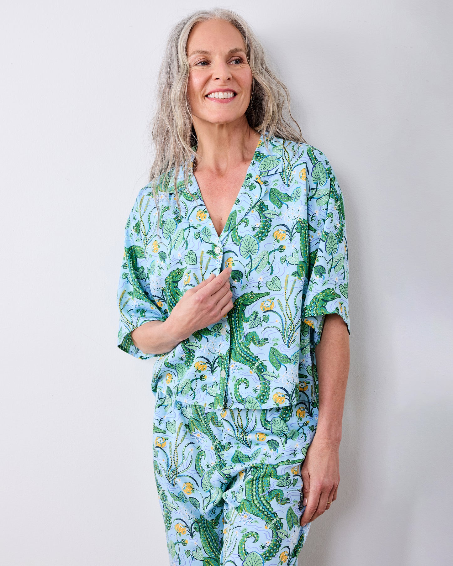 Front three-quarter view of the gator-print pajama top and matching pants against a light wall