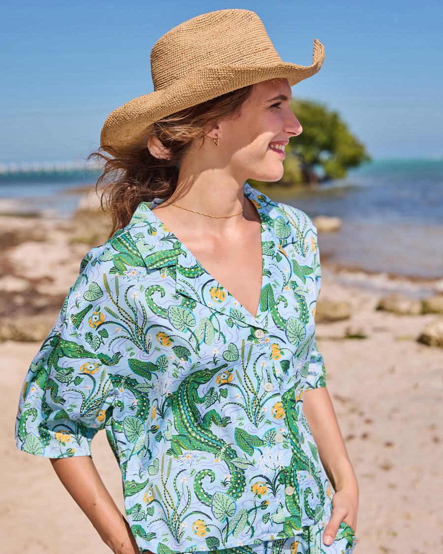 Waist-up view of the button-front gator-print pajama top worn with matching pants on a beach