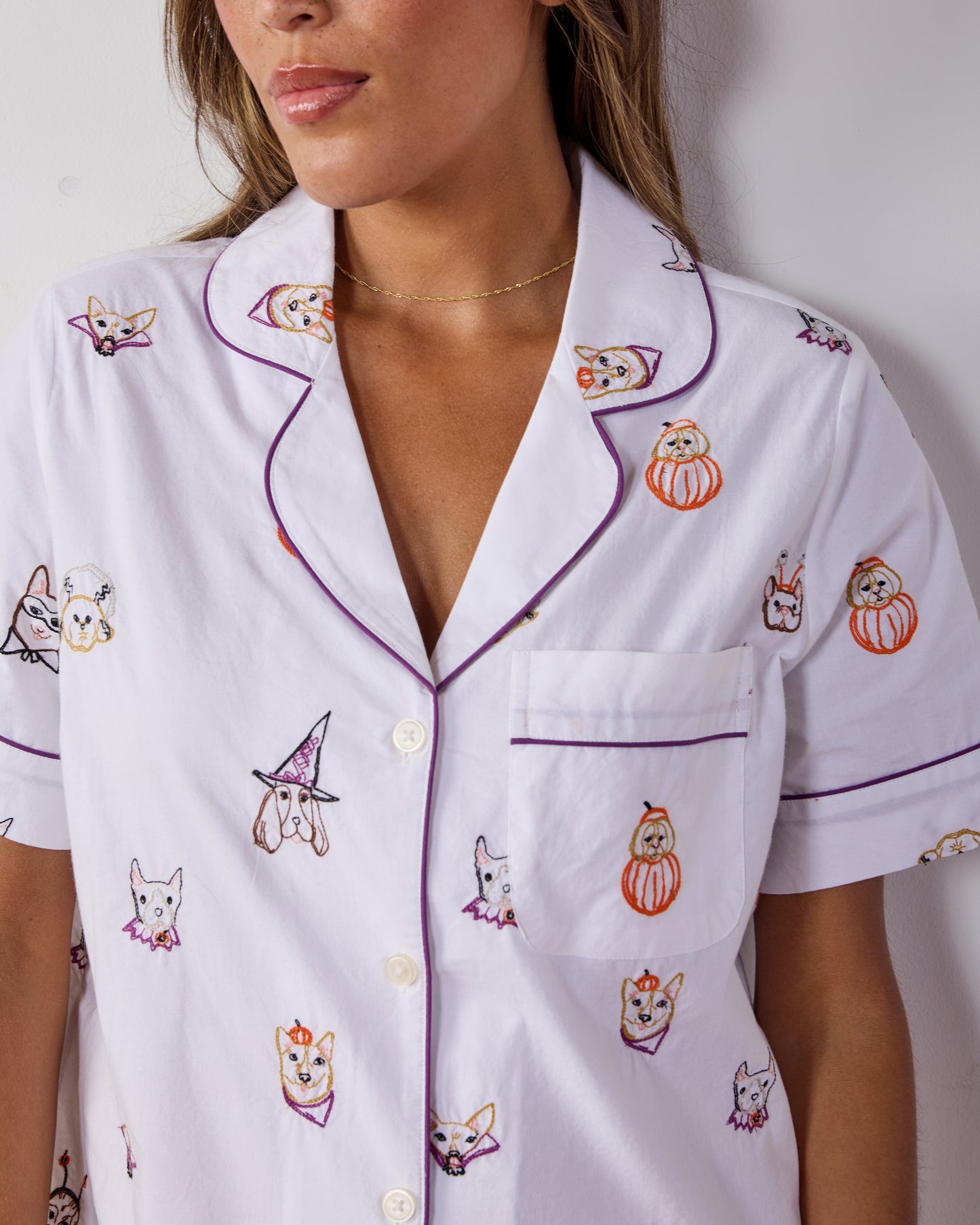 Close-up of the Halloween Hounds pajama top showing purple piping, buttons, chest pocket, and dog costume print.