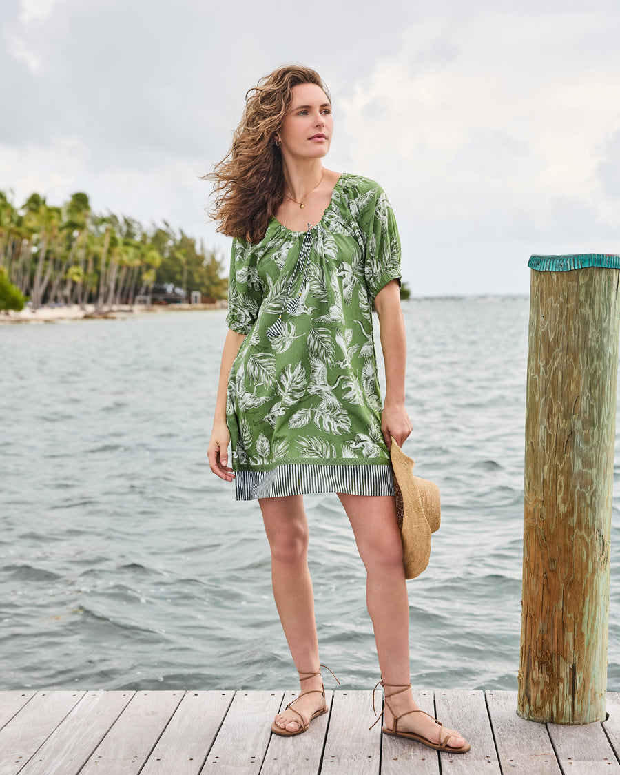 Full front view of the olive grove Annie Dress with gathered tie neckline, leaf-and-heron print, and striped hem