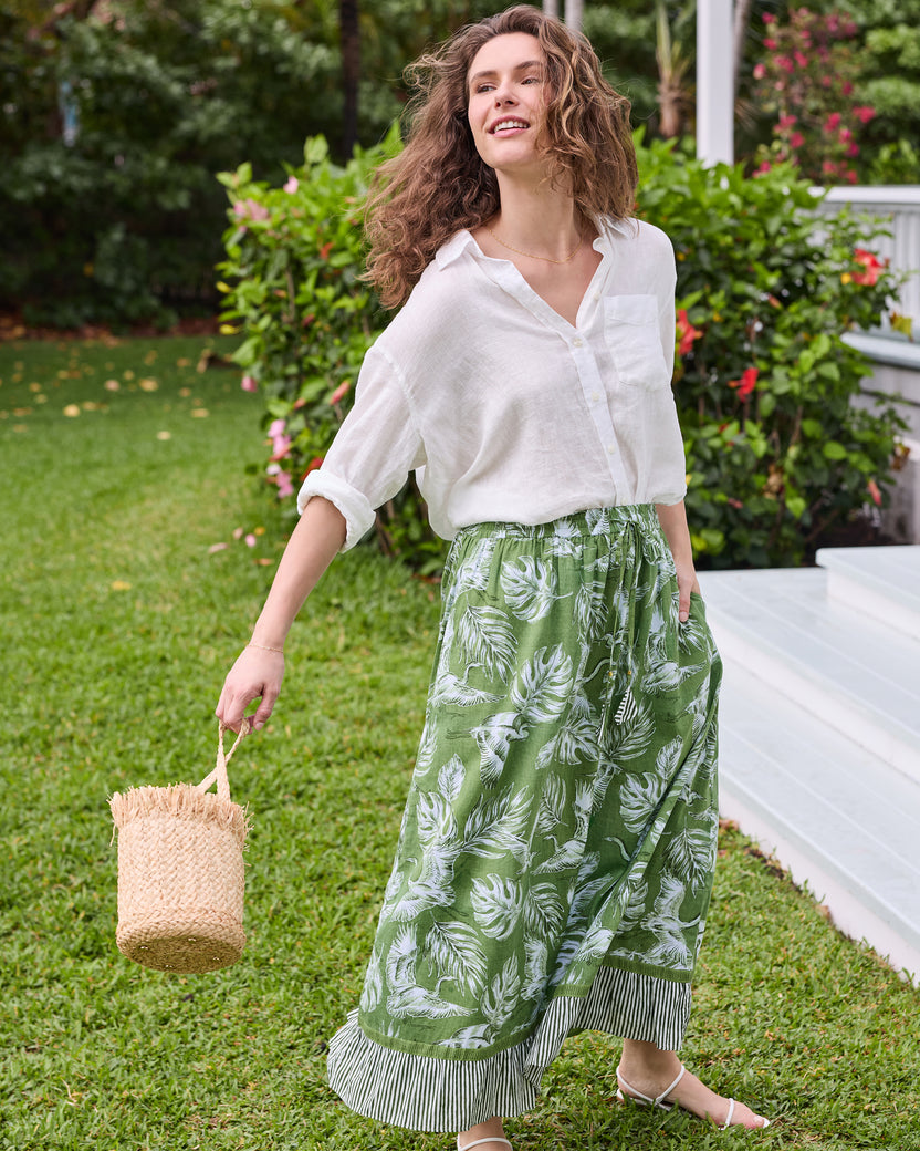 Three-quarter view of the olive green Devon Skirt with white heron and palm print, drawstring waist, and striped hem