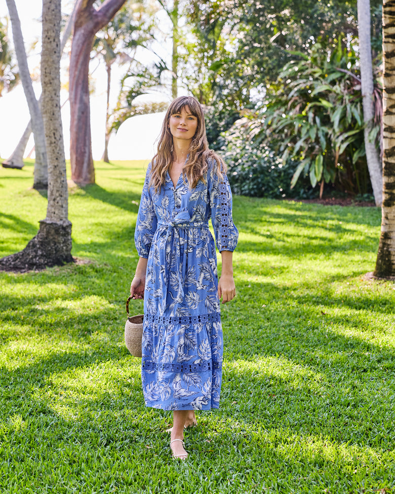 Full-length front view of the saltwater blue Monroe dress with a heron-and-leaf print, tie belt, and lace panels