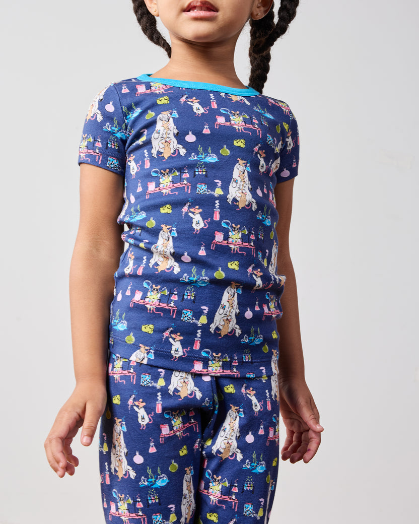 Close view of the blue short-sleeve pajama top and matching pants, showing the colorful laboratory-themed print and bright blue neckline.