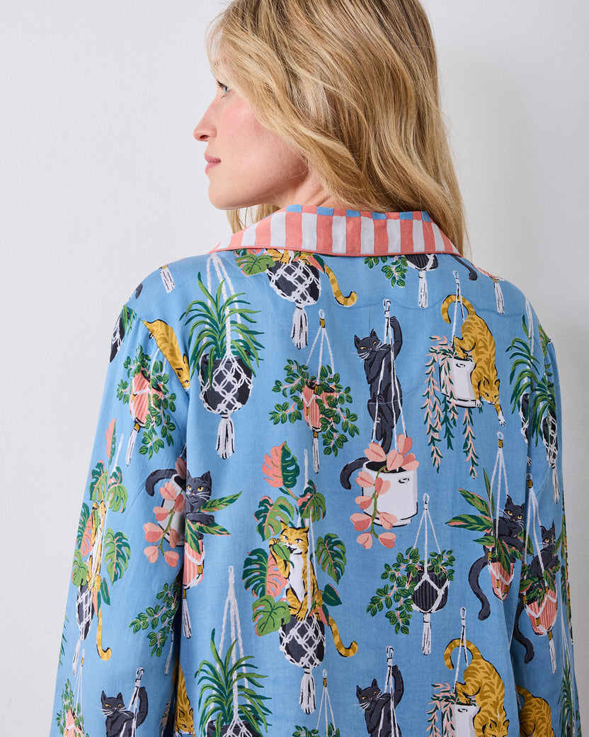 Back detail of the slate-blue pajama top showing the cat-and-houseplant print and striped collar
