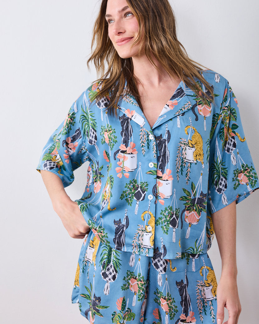 Front view of the slate-blue short pajama set with cats and hanging potted plants