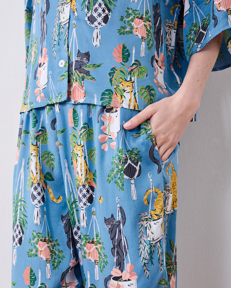Close view of a hand inside the pajama pants pocket and the cats with hanging plants print