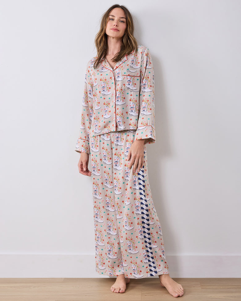 Full-length front view of the long-sleeve, wide-leg pajama set indoors, showing the cowboy-boot print and contrasting pants side panel.