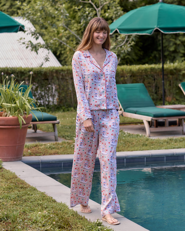 Full-length front view of the long-sleeve, wide-leg pajama set beside a swimming pool, showing the floral cowboy-boot print.
