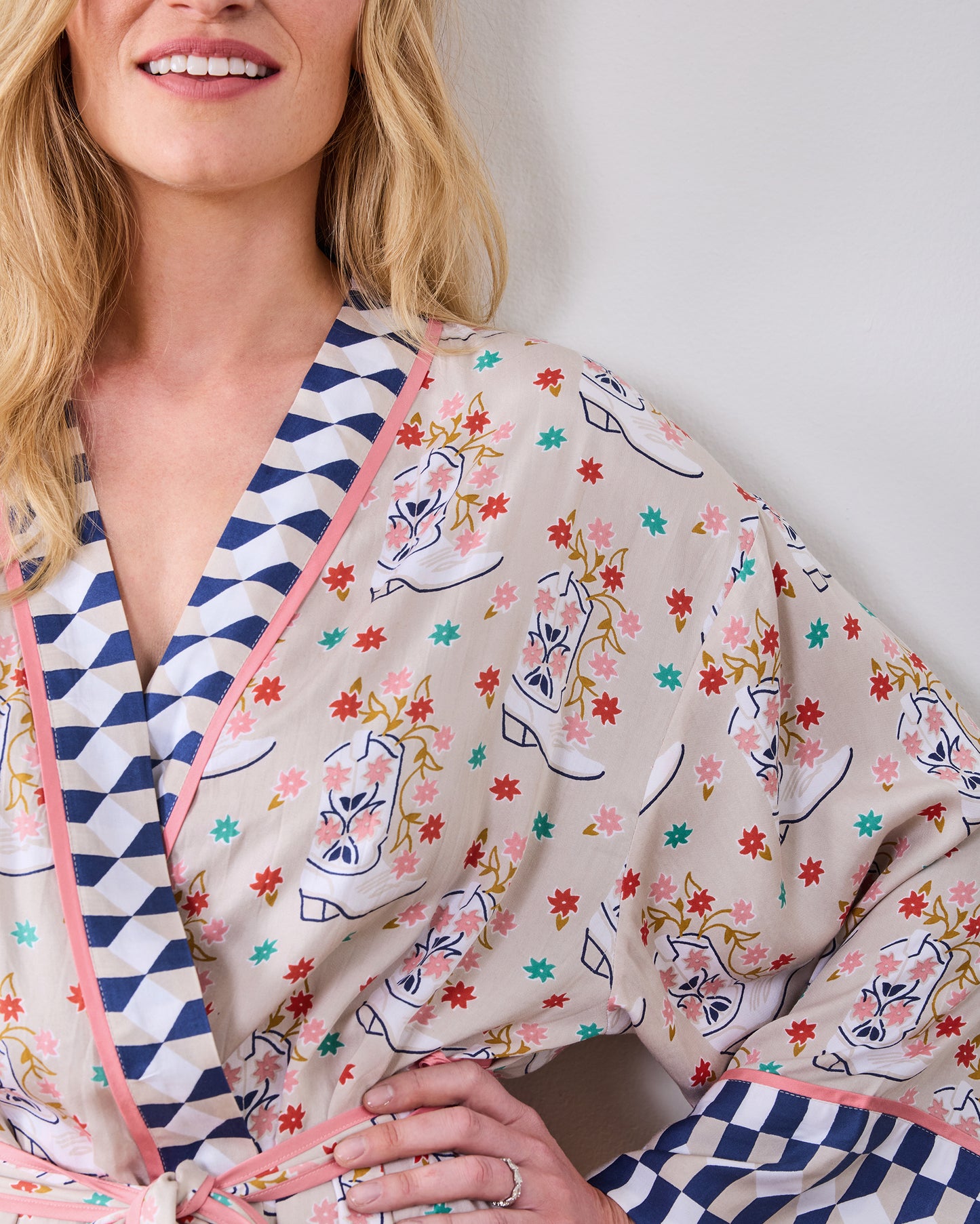 Close-up of a printed robe showing the notched collar, pink edging, checkerboard trim, and tied belt.