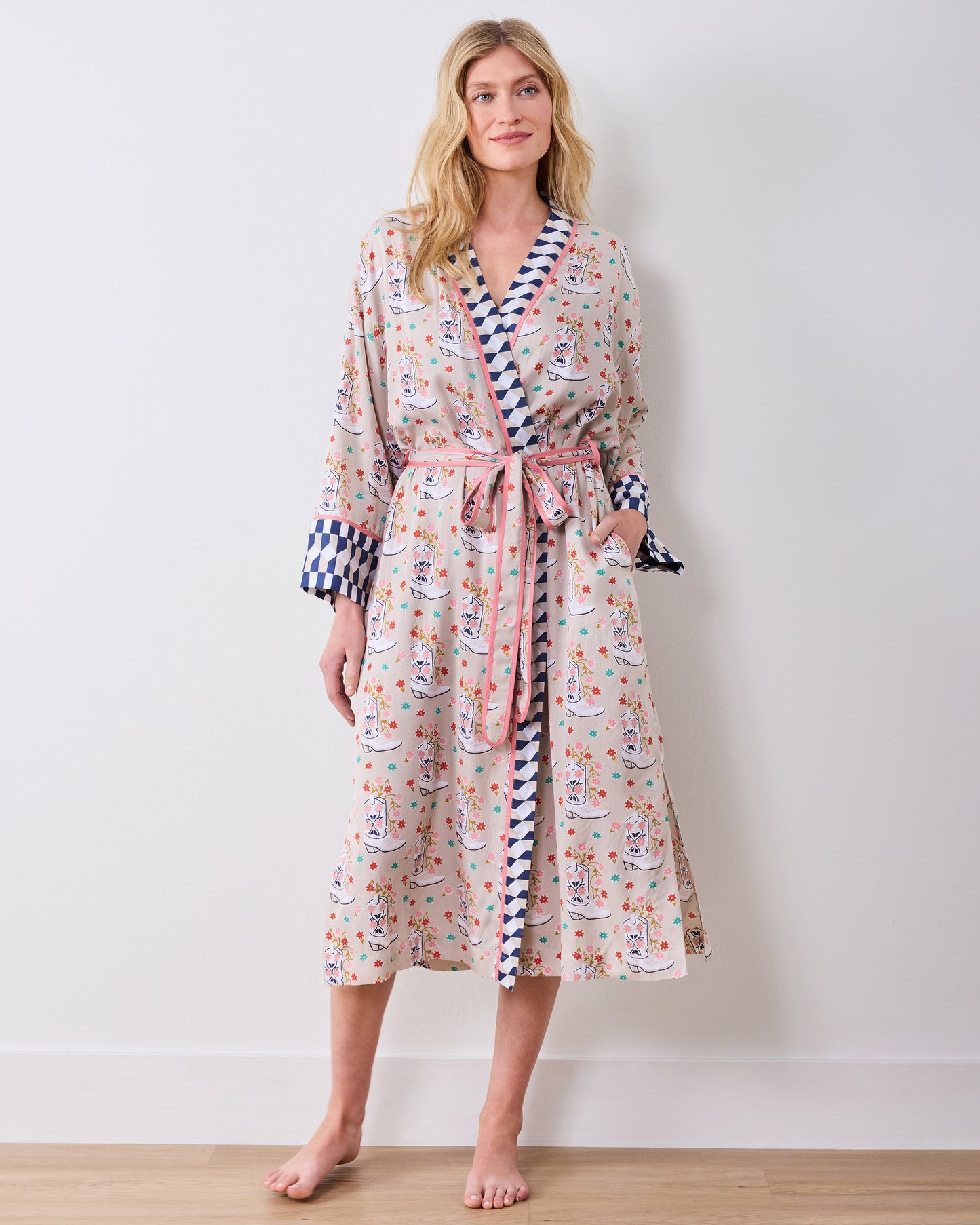 Model standing barefoot and wearing a printed knee-length robe with a tied belt and contrasting blue-and-white checkerboard trim.
