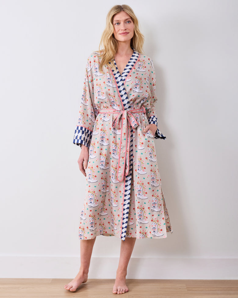 Model standing barefoot and wearing a printed knee-length robe with a tied belt and contrasting blue-and-white checkerboard trim.