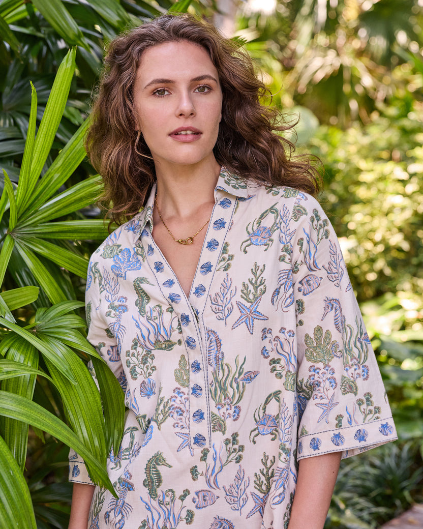 Upper-body front view of the sand-colored Goa Dress with a collar, wide sleeves, and blue-and-green sea-life print