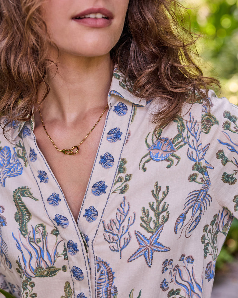 Close-up of the sand-colored Goa Dress neckline and blue-and-green sea-life print, including shells, crab, lobster, starfish, and seahorse motifs