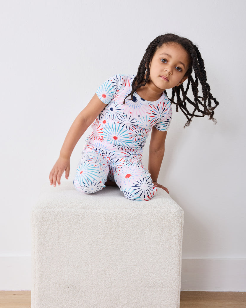 Child model kneeling in the fireworks-print short-sleeve pajama set