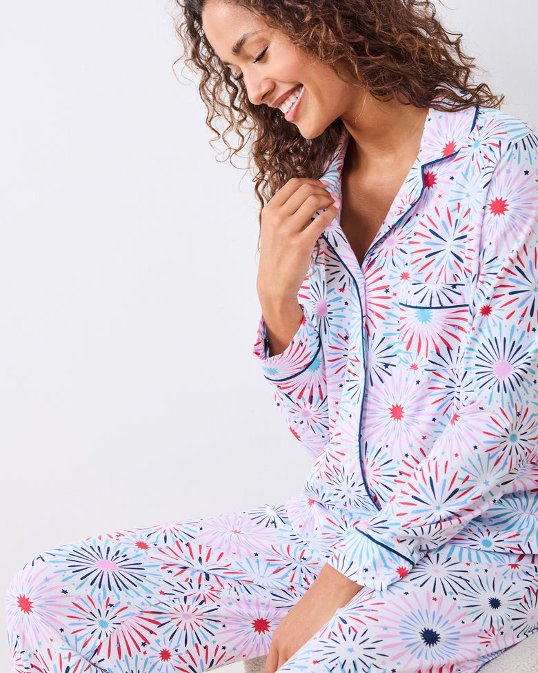 Seated studio view of the fireworks-print long pajama set with navy piping