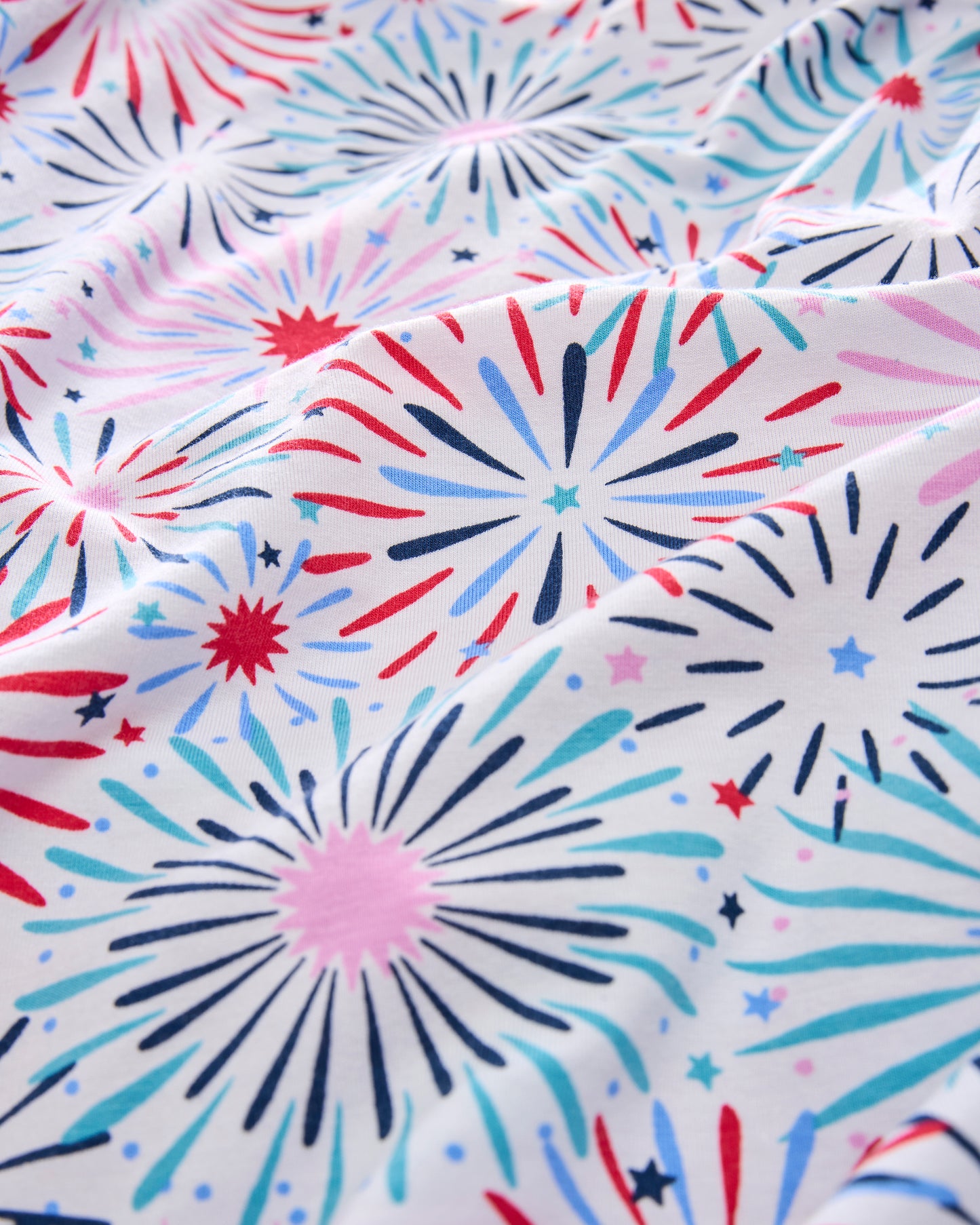 Close-up of the white pajama print with red, pink, blue, and navy fireworks and stars