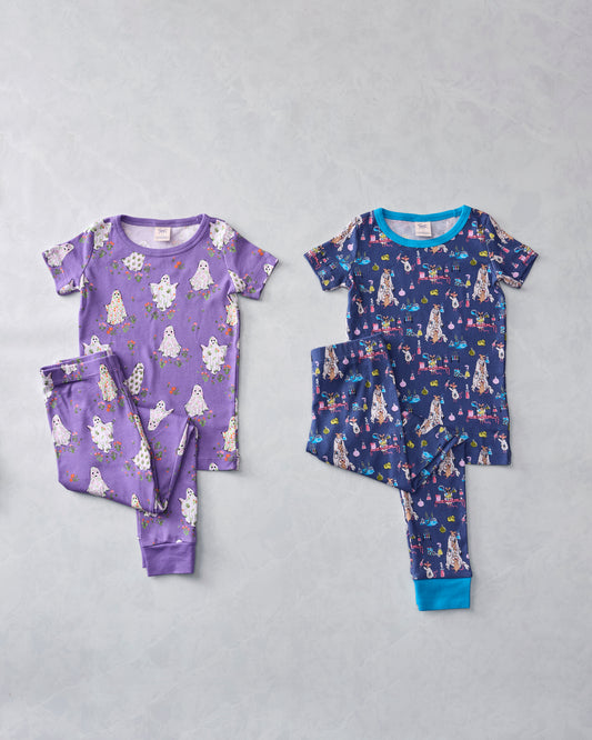 Two children's short-sleeved pajama sets displayed flat: a purple ghost-print set and a navy monster-print set.