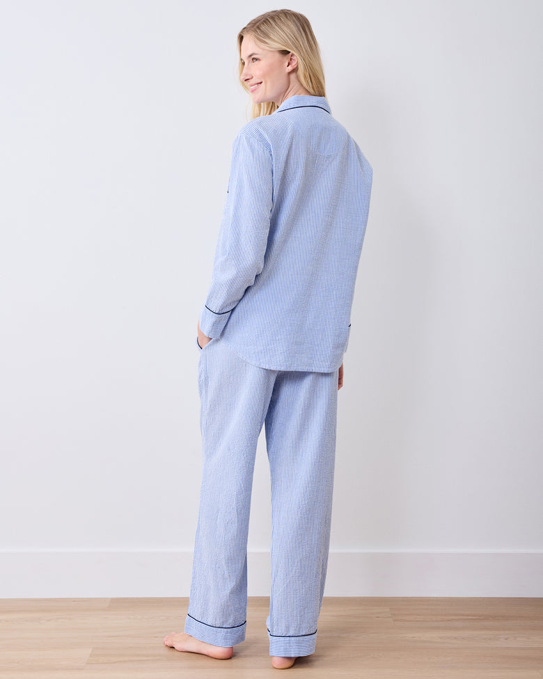 Rear three-quarter view of a blue-and-white striped long pajama set with dark piping at the cuffs