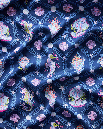 Navy print with repeating seahorses, shells, coral, seaweed, pearls, and starfish