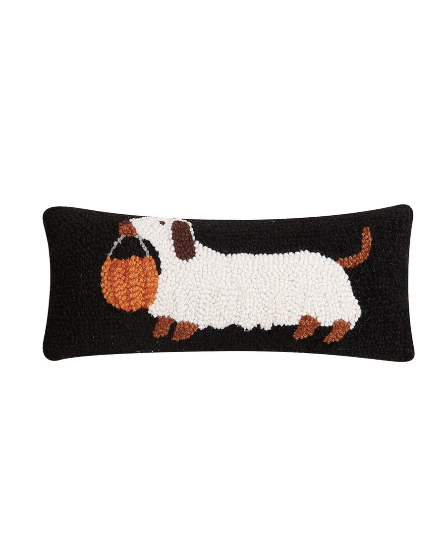 Black rectangular hooked pillow featuring a white dachshund carrying an orange pumpkin bucket.