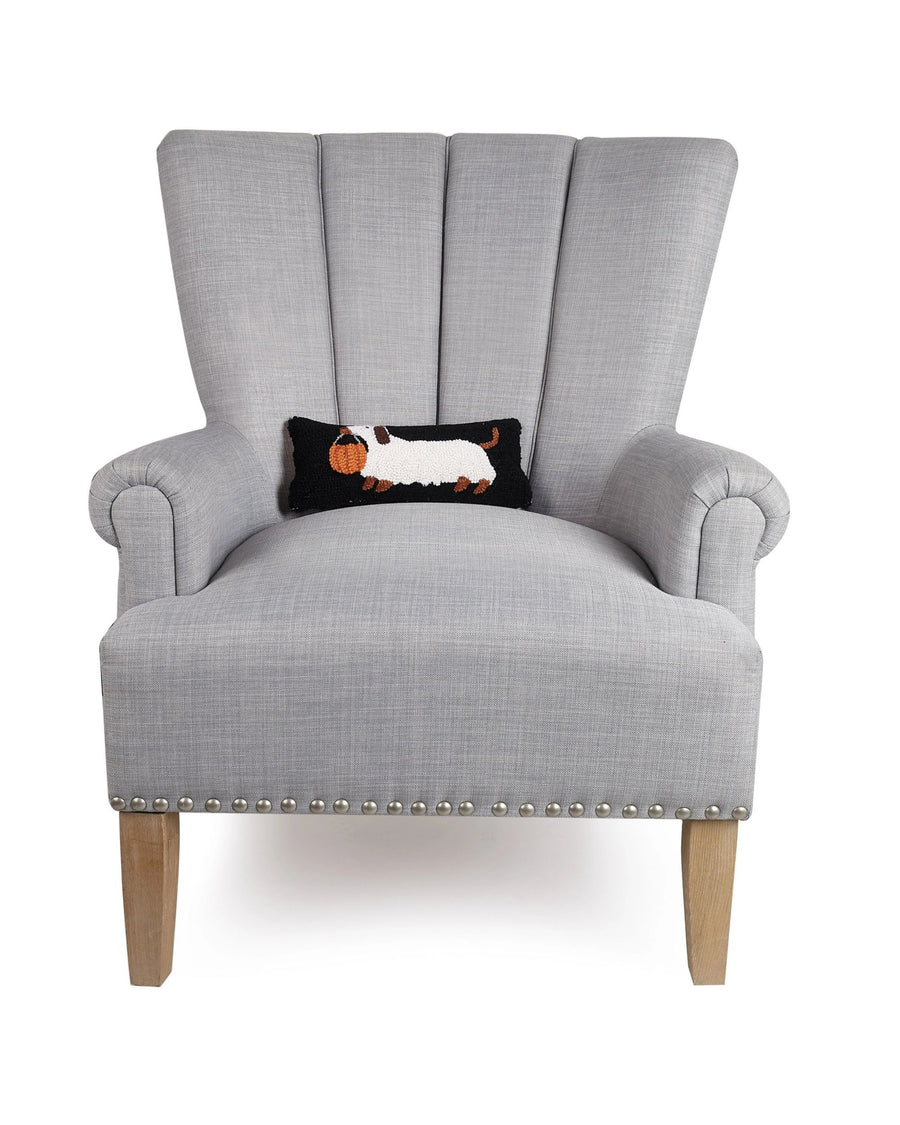 Gray wingback chair displaying the black dachshund Halloween pillow.