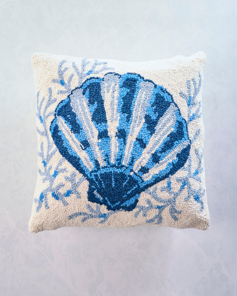 Square accent pillow with a large blue scallop shell design and blue botanical details on a light background.