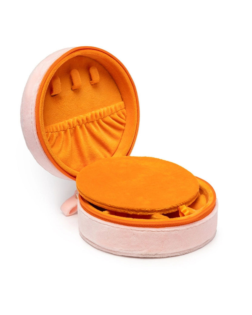 Open pink round jewelry case with orange lining, a gathered pocket, and ring slots.