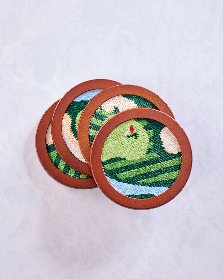 Four overlapping round green stitched golf coasters showing varied sections of the golf-themed designs.