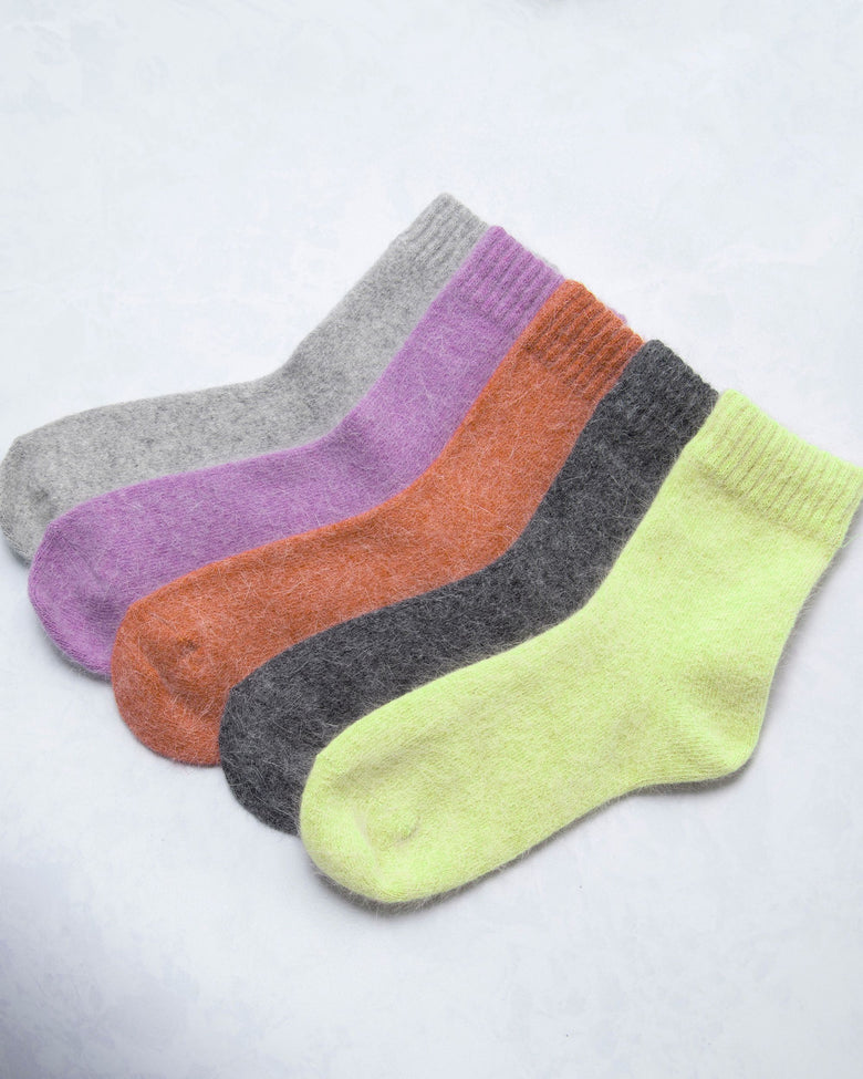Five cozy socks arranged diagonally in gray, purple, orange, charcoal, and lime green.