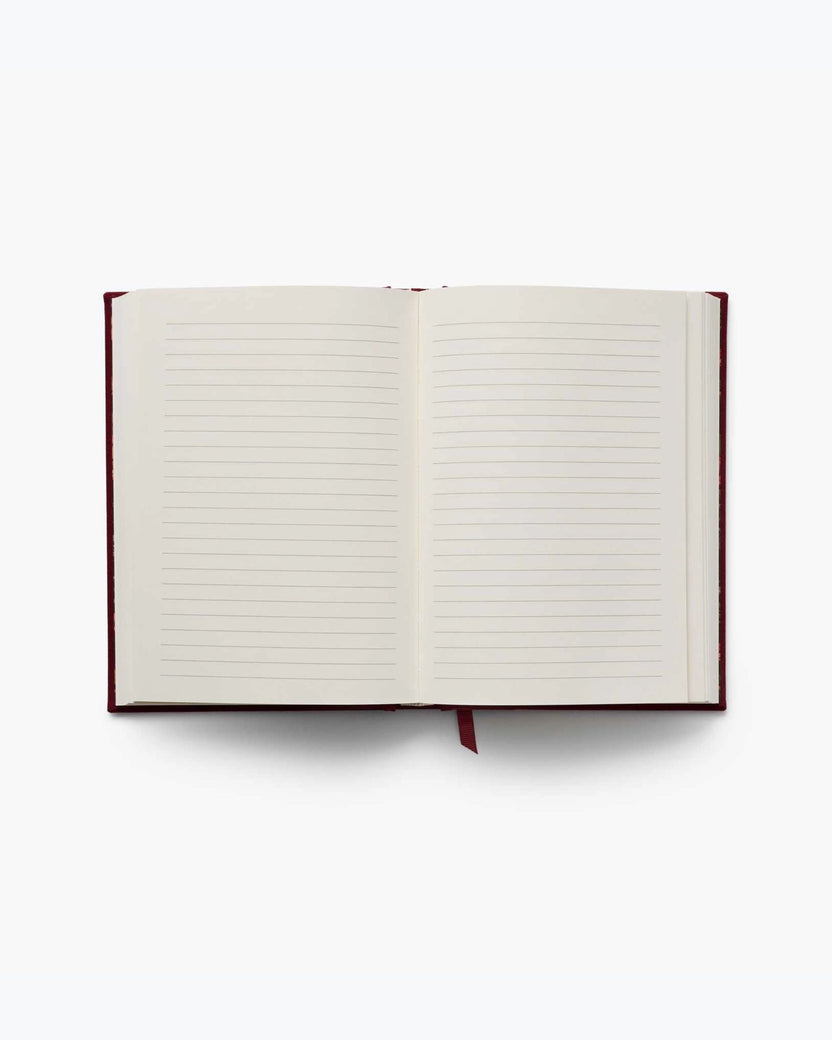 Gracie journal opened to two blank lined pages with a red ribbon bookmark.
