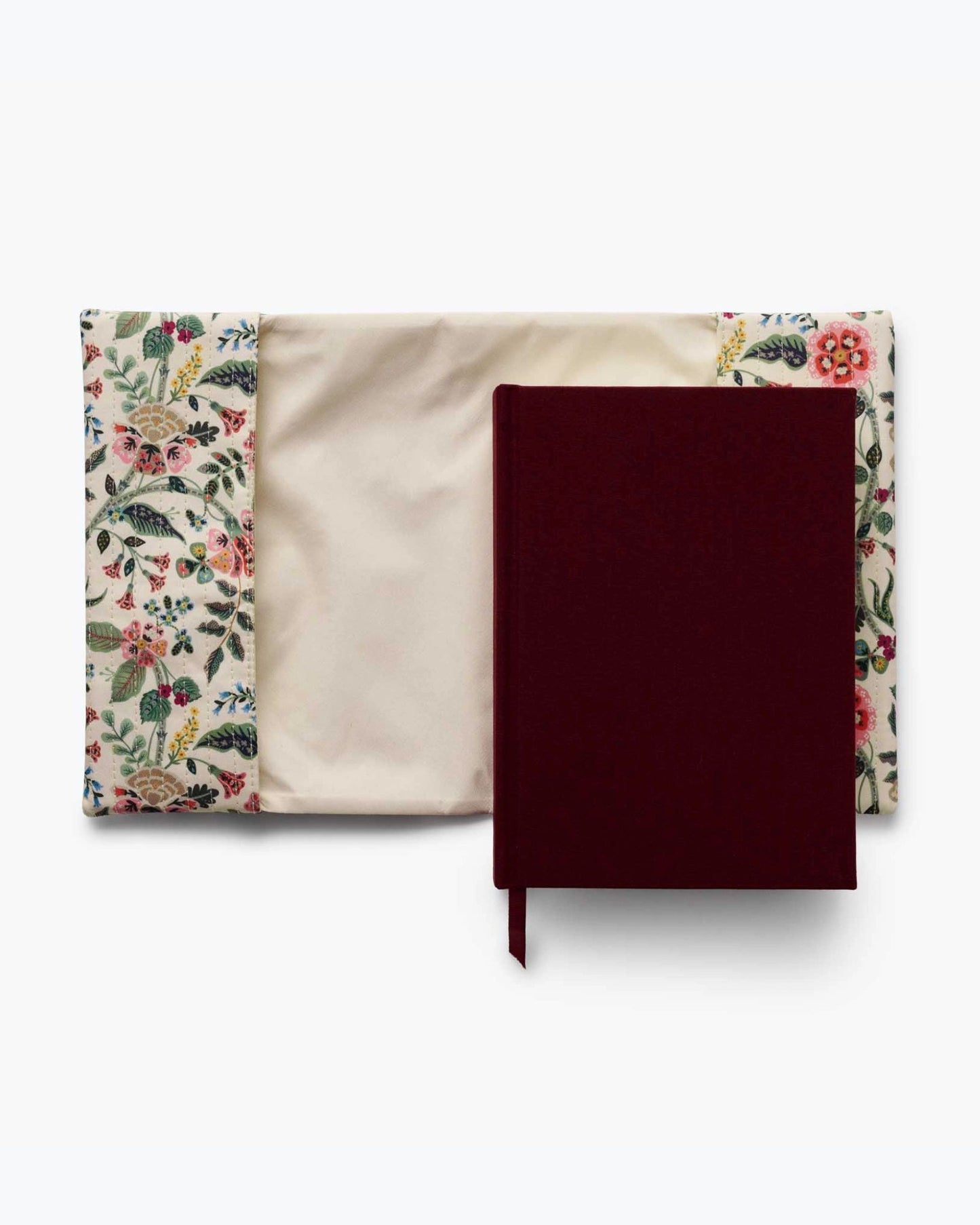 Gracie journal with its burgundy cover resting on a cream floral quilted cover, showing the removable cover and journal interior.