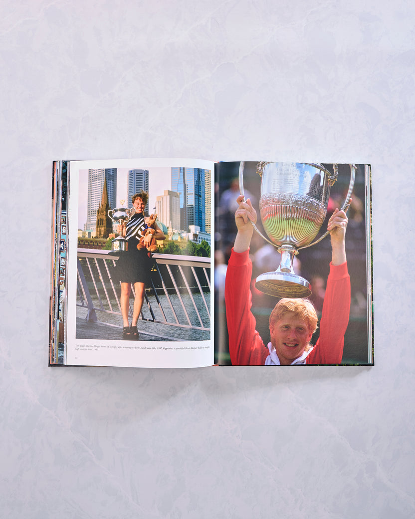 Open book showing one tennis player holding a trophy and another raising a large trophy.