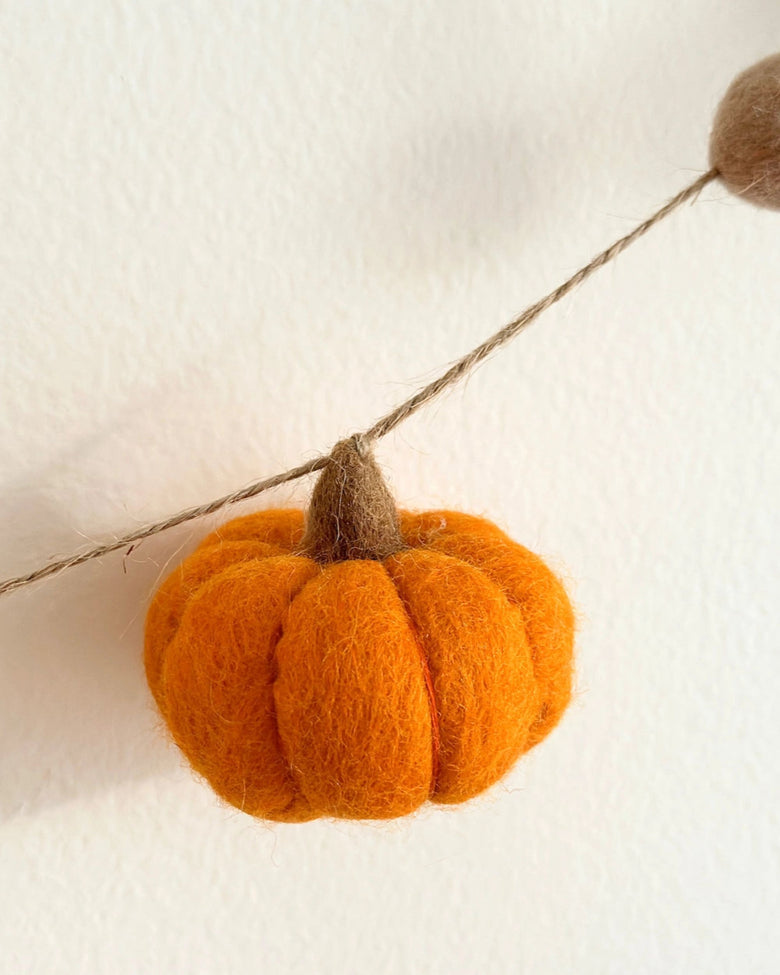 Close-up of an orange pumpkin ornament attached to the garland string.