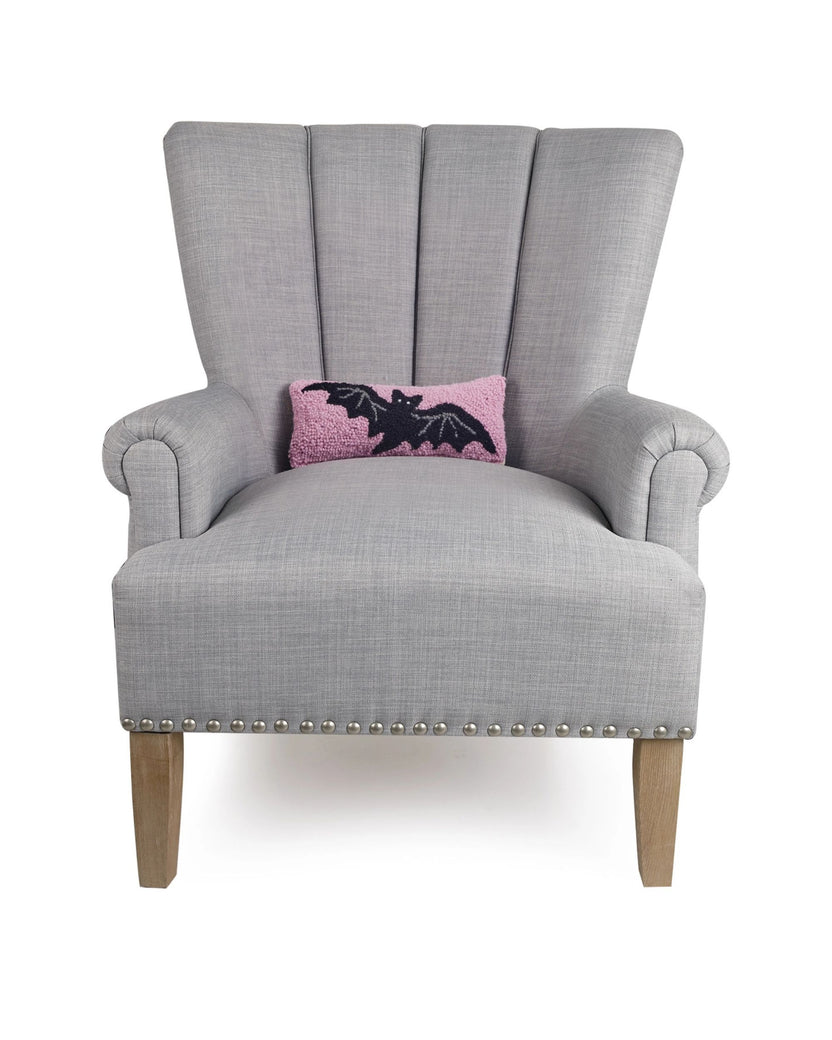 Gray wingback chair displaying the pink bat accent pillow.