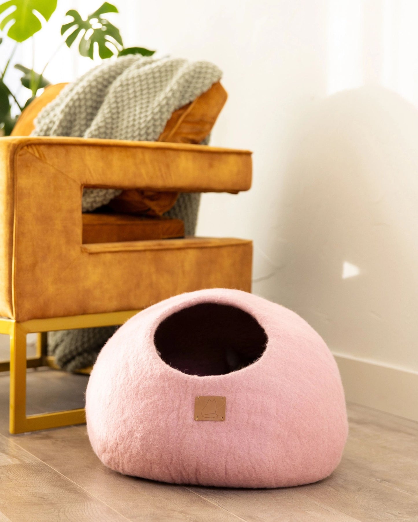 Pink cave-style cat bed shown in a room with its opening facing forward.