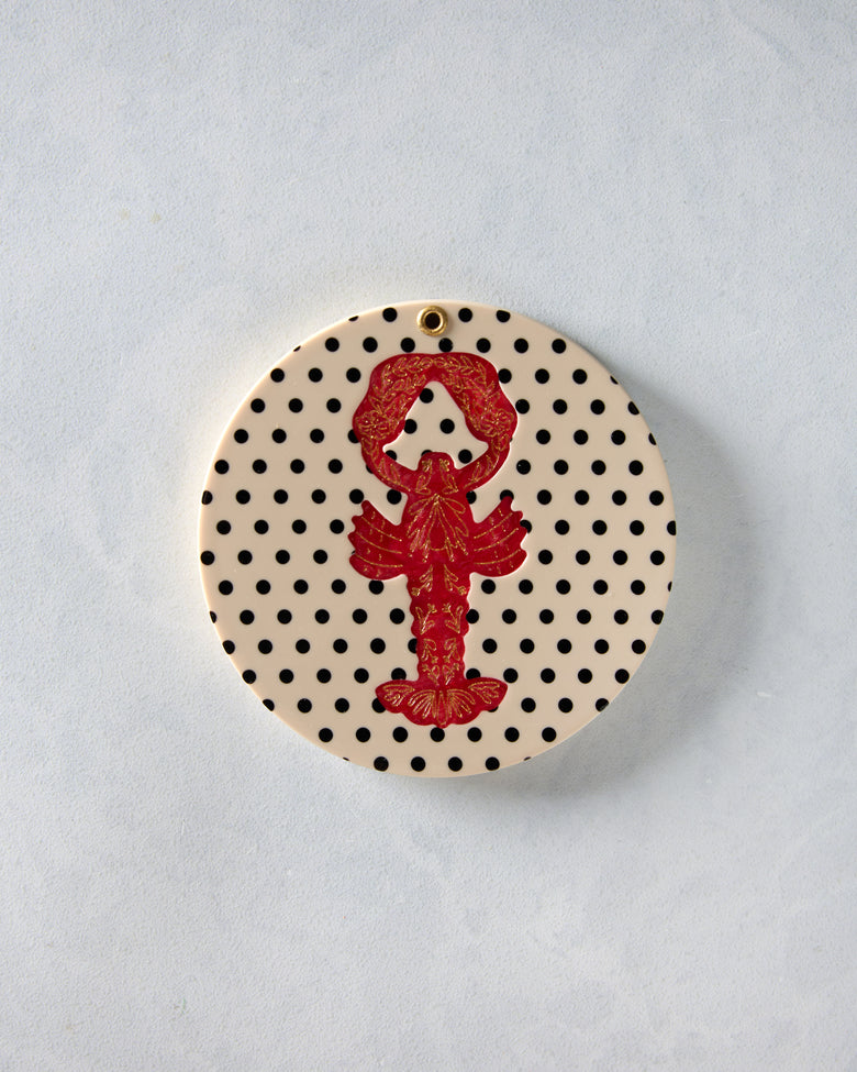 Closed round compact mirror with a cream cover, black polka dots, and a red lobster design.