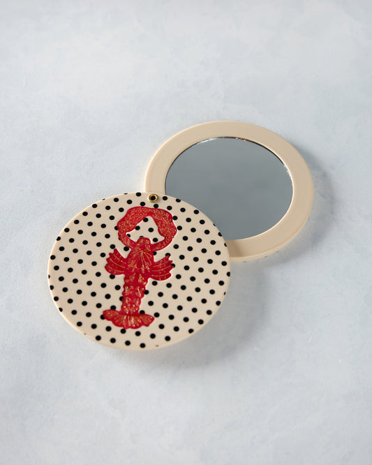 Open lobster compact mirror showing the reflective mirror and cream-and-black polka-dot cover with red lobster design.