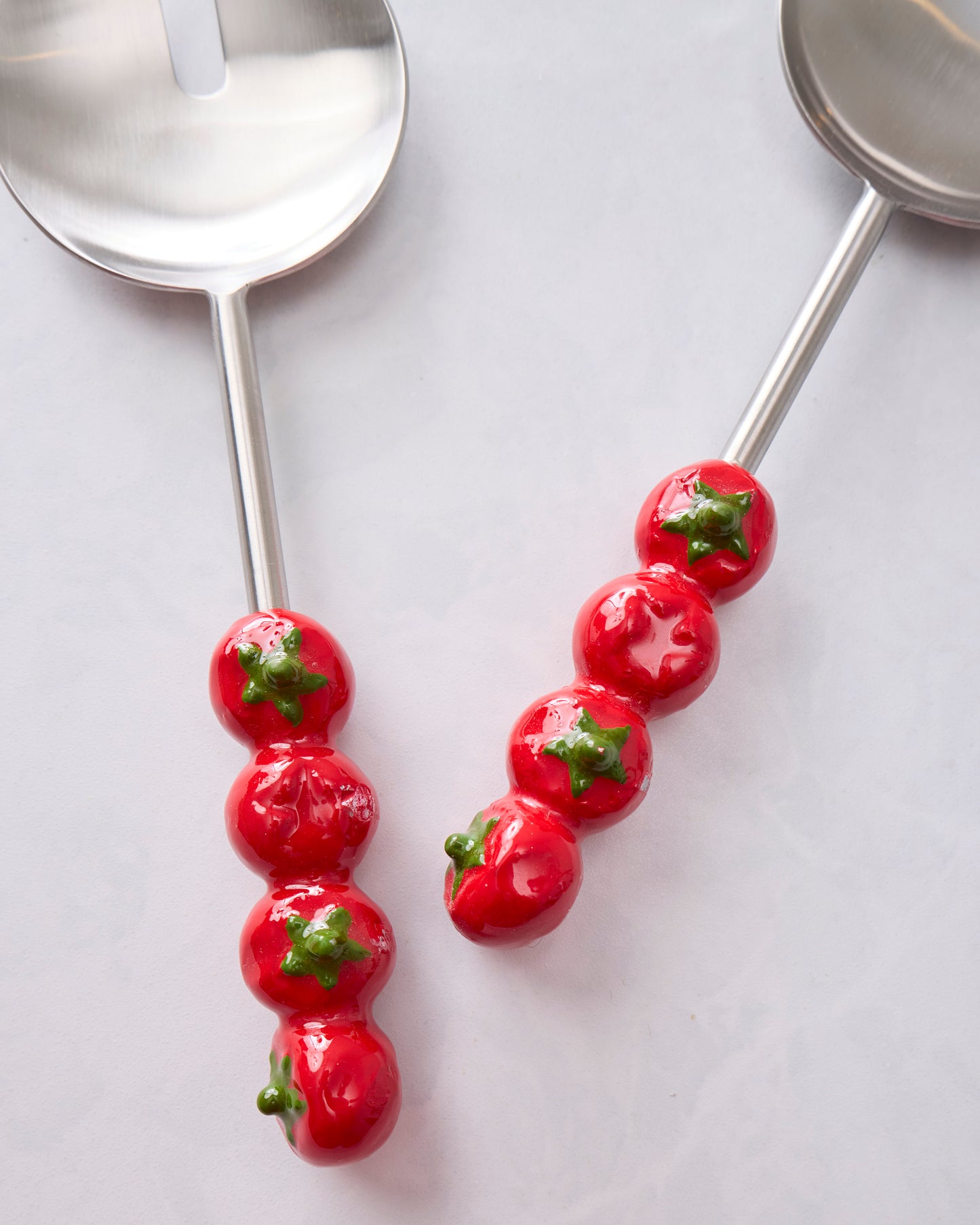 Close-up of the red tomato-shaped handles on the salad server set