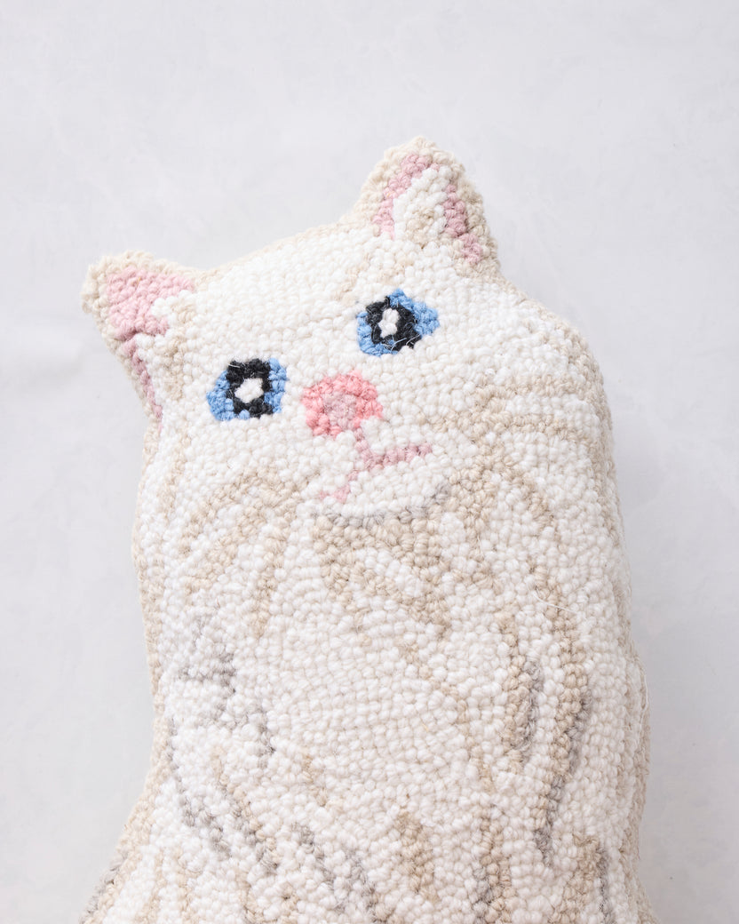 Close-up of the white cat-shaped hook pillow front with pink ears and nose, blue eyes, and stitched whiskers