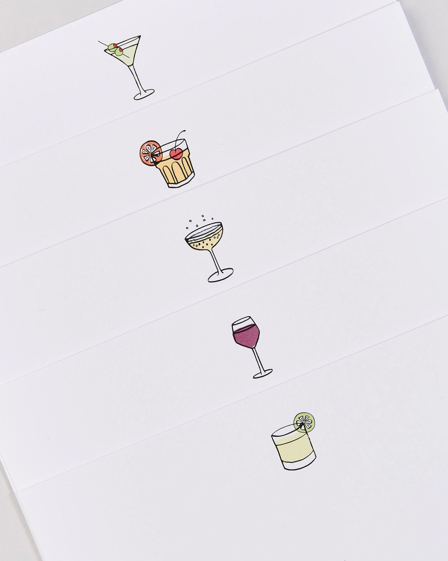 Angled close view of five white cocktail-themed notecards with illustrations of assorted drinks and garnishes.