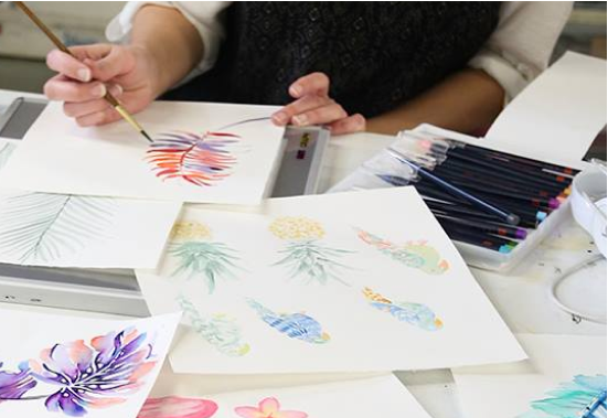 Person painting colorful illustrations on paper beside art supplies, accompanying Printfresh’s design-history timeline.